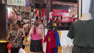 Chatuchak market çalışanları sıralı kıyafetlerin arasında yürüyen şeylere bakıyor Asyalılar Avrupalılar Tayland Bangkok 04.05.2025