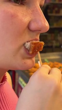 Chatuchak pazarı, tezgâhtar kızın üzerinde Tayland usulü ızgara domuz eti tadıyor. 04.05.2025