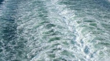 Yavaş çekimde, denizde büyük bir yolcu feribotunun arkasındaki uyanma görüntüsü. Geminin hareketinden oluşan geminin yanındaki mavi deniz suyunda beyaz köpük izi. Yüksek kalite 4k görüntü