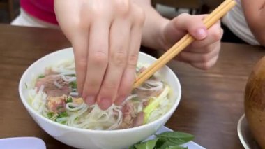 Bir el Bangkok 'un hareketli restoranlarında bir kase pho' nun üzerine limon sıkıyor, bulaşık tadını arttırıyor. Yüksek kalite 4k görüntü