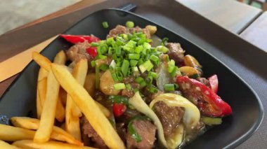 Otantik biftek soslu sığır bifteği sıcak bir tabakta biraz sebze ve patates kızartmasıyla servis edilir. Yüksek kalite 4k görüntü