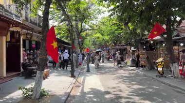 Güneş parlıyor, çok sıcak, kızlar güneş ışınlarından kendilerini şemsiyelerle kaplıyorlar Hoi Şehir halkı Vietnam Hoi 05.05.2025