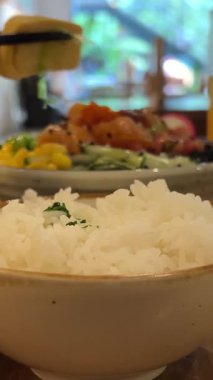 Kore usulü kızarmış tavuk ve salata, portakal suyuyla birlikte beyaz bir masada pirinç kasesinde. Yüksek kalite 4k görüntü