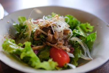 Sıcak salatayı dana eti, marul karışımı ve ızgara sebzeyle kapat. Mantar, patlıcan, kabak, domatesler ahşap masada seramik tabakta. Seçici odaklanma. Yüksek kalite fotoğraf