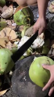 Korkusuz satıcı keskin palayla hindistan cevizi kesiyor. Hindistan cevizi doğrama elleri