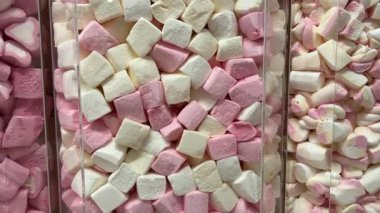 Makro, bir tepsi yumuşak fıçı şeklindeki, pembe ve beyaz şekerlemeli şekerleme yığınının yavaş çekimini yapıyor. Yüksek kalite 4k görüntü