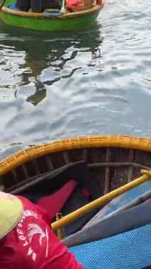 Bambu ve rattan yapılmış Asya yapımı yuvarlak sepet tekne. Zümrüt yeşili sularda sallanan sepet tekne. Kıyı bölgesinde balıkçılar tarafından kullanılan sepet teknesi. Hoi Bir Vietnam 05.20.25