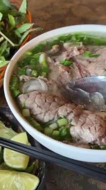 Taze hazırlanmış Vietnam pilavı, taze bitkilerle taze limon suyu ve fasulye filizi. Kadın otantik Vietnam lezzetlerini arttıran malzemeler ekliyor. Sıcak Vietnam çorbası. 