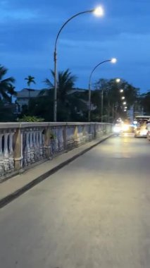 Köprü üzerinden gece turistleri ve motosikletle gelen turistler parlak fenerleri ve Vietnam Hoi mağazalarını geçtiler. 05.20.2025