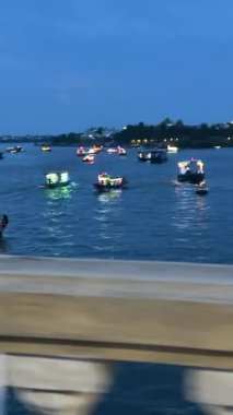 Köprü üzerinden gece turistleri ve motosikletle gelen turistler parlak fenerleri ve Vietnam Hoi mağazalarını geçtiler. 05.20.2025