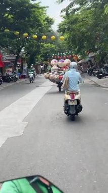 Bisikletli ve arabalı insanların yanından geçerken yolu çek. Vietnam Hoi 'nin merkez caddesi. 05.20.2025.