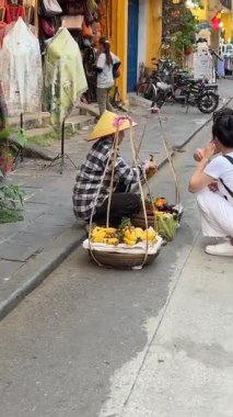 Yeryüzündeki bir kadın Vietnam çöreği, ev yapımı turtalar satıyor, turistler oturuyor, Vietnam 'daki yerel nüfus ile iletişim kuruyor. 05.20.25