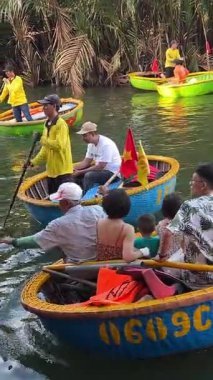 Renkli yuvarlak botlar canlı bir nehirde yüzerler, Hoi An, Vietnam 'ın kültürel çekiciliğini sergilerler, yemyeşil palmiyeler ve neşeli aktivitelerle çevrili. Hoi An Vietnam 05.04.2025