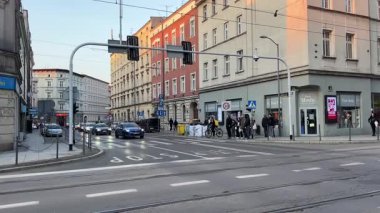 Soğuk bir günde yayalar yaya geçidinde yürür bisikletle turistlerin arkasından çekim yapan çantalar taşır Polonya yerlileri 06.20.2025