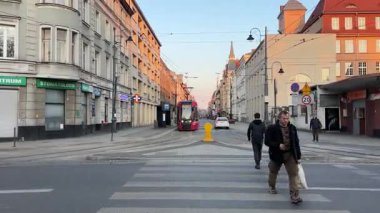 Soğuk bir günde yaya geçidinden geçen insanlar Polonya Katowice 06.20.25 'ten geçen bir tramvay.