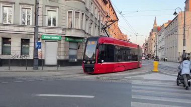 Şehir merkezinde tren rayları üzerinden geçen kırmızı bir tramvay Polonya Katowice 06.20.2025