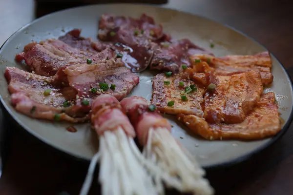 Domuz pastırması ve et ızgarasına sarılı Enoki mantarları yakın plan..