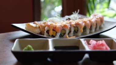 Modern bir restoran atmosferinde servis edilen lezzetli ve güzel bir suşi tepsisinin tadını çıkarın. Yüksek kalite 4k görüntü
