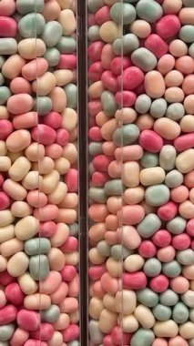 Makro, bir tepsi yumuşak fıçı şeklindeki, pembe ve beyaz şekerlemeli şekerleme yığınının yavaş çekimini yapıyor. Yüksek kalite 4k görüntü