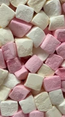 Makro, bir tepsi yumuşak fıçı şeklindeki, pembe ve beyaz şekerlemeli şekerleme yığınının yavaş çekimini yapıyor. Yüksek kalite 4k görüntü