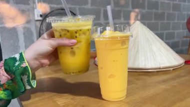 Mango suyu, bambu kamışı, yarım taze mango, sarı frangipani çiçeği ve arka planda kaynayan mavi yüzme havuzu. Mango suyu içecekler.