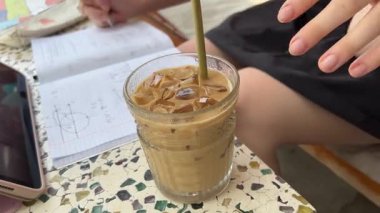  Deniz manzarası, bir kadın ferahlatıcı bir içecek içiyor, bir bardak soğuk kahve ile su damlacıkları ve masada bardaklar. Yüksek kalite 4k görüntü