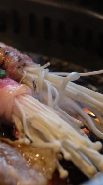 Kore 'nin geleneksel kömür tavası ocağında ızgara yapılırken Kore barbeküsünde fırında servis edilen Galbi.Kore ızgara eti mantarı için seçici odak noktası. 