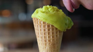 yeşil renkli dondurma yavaş çekimde kepçeleniyor. Dişi dil, dondurmayı üç kat lezzetli yalıyor.