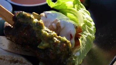 Seçici odaklanma. Lezzetli et şişleri gri tavada kızarıyor. Yağda pişirilmiş koyun kebabı. Kadın elleri dönüyor ve gri barbekü tavasında et şişleri pişiriyor..