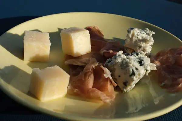 Şarküteri tahtası, peynir tabağı, bir el tahta kürdanla bir küp gouda peyniri diker. Yüksek kalite 4k görüntü