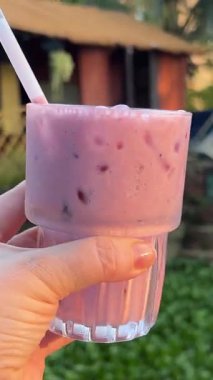 Buzlu, buzlu, buzlu ve naneli bir içecekle dolu cam bir bardağın videosu. Birkaç cam pencerenin önünde bir caddeyi gösteriyor. Yüksek kalite 4k görüntü