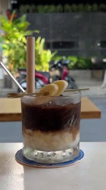 Buzlu, muzlu, buzlu, buzlu kahve bardağının üstüne krema serpilmiş espresso serpiştirilmiş bisküvi çubukları ve rulo gofretle süslenmiş. Katmanlı içecek dinleniyor. 4k