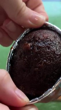 Çikolatalı keki çikolatalı şekerlemeyle tutan bir el. Şekerleme kekin üzerine serpilmiş. Yüksek kalite 4k görüntü