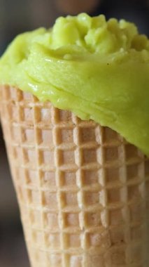 yeşil renkli dondurma yavaş çekimde kepçeleniyor. Dişi dil, dondurmayı üç kat lezzetli yalıyor.