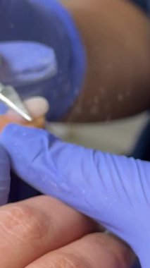 Manikür ustası müşterileri güzellik salonuna çivilemek için elektrikli makine kullanıyor. Tırnak sanatları ustası parmaklarını cilaya ve dosyalara hazırlar. Manikürcü tırnaklarını parlatır. .