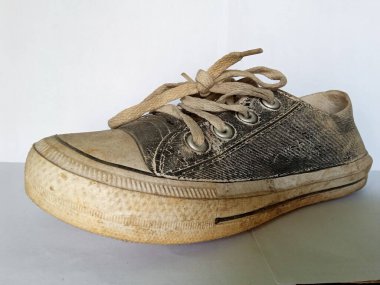 Beyaz arka planda yıpranmış ve kirli ayakkabılar