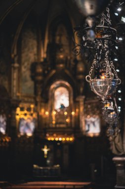 Hafifçe parlayan kilise mumu ışıkları asıyor, kutsal bir yerde sıcak ve hürmetkar bir ortam yaratıyor.