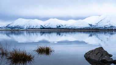 Lake Heron, hills covered in snow reflected in water, winter in New Zealand clipart