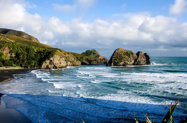Pasifik Okyanusu plajı Yeni Zelanda 'da kayalarla çevrili, siyah kum, dalgalar
