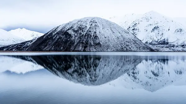 Heron Tepesi karla kaplı, suya yansıyor, Yeni Zelanda 'da kış.