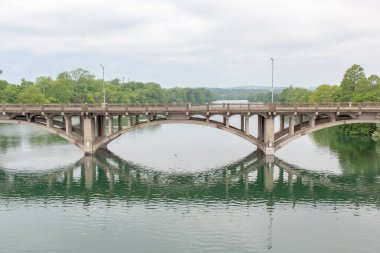 Su üzerinde eski bir taş köprü yansıması. Fotoğraf Austin Texas 'taki Lady Bird Gölü' nde bulutlu bir günde çekildi.