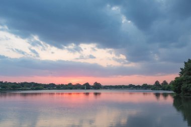 Ağaçlı ufukta dramatik günbatımı bulutları yansıyor. Fotoğraf Woodlawn Lake San Antonio Texas 'ta çekildi.