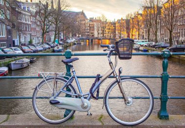 Bina boyunca park etmiş bisiklet Amsterdam 'da kanallarda yüzüyordu. Fotoğraf Amsterdam Hollanda 'da gün batımında çekildi