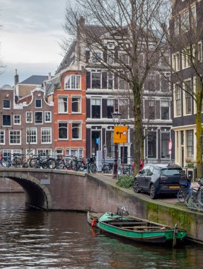 Amsterdam 'daki bina boyunca park etmiş yeşil bir tekne. Fotoğraf Amsterdam Hollanda 'da gündüz çekilmiş.