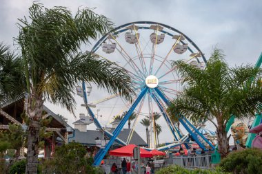 Kemah Board Walk Ferris wheel surrounded by green palm trees. Photo taken at the Kemah Board Walk in Houston Texas on a cloudy day clipart