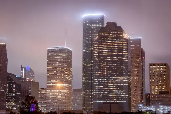 Houston Teksas şehir merkezi gökdelenleri aydınlatılmış binalar. Fotoğraf bulutlu bir gecede çekildi.