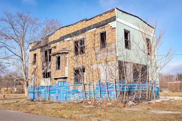 Bulutlu bir günde Detroit Michigan 'da terk edilmiş, mavi desenli, eski, tahta kaplı bir ev.