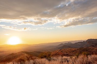 Teksas 'taki Big Bend Ulusal Parkı' nın çim tarlalarında ve çöllerinde dramatik bir altın gün batımı bulutu.