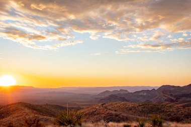 Teksas 'taki Big Bend Ulusal Parkı' nın çim tarlalarında ve çöllerinde dramatik bir altın gün batımı bulutu.