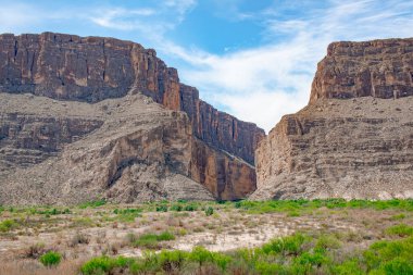 Texas 'taki Big Bend Ulusal Parkı' ndaki çöl ve kaya kayalıklarının manzarası. Fotoğraf bulutlu mavi bir gökyüzünde çekildi.